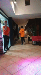 Two men perform indoor singing act in orange outfits