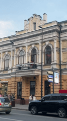 Street view of an ornate light yellow building with classical details