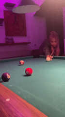 Pink-haired woman plays billiards in purple-lit Barcelona room