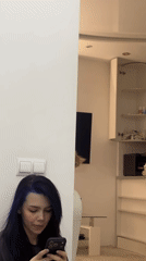 Woman uses smartphone against white wall in Khimki