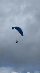Paraglider flies under cloudy skies in Kuta Selatan