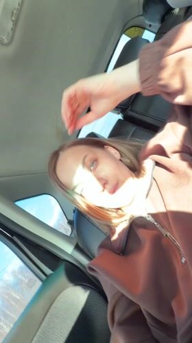 Woman in car passenger seat touches forehead in Russia
