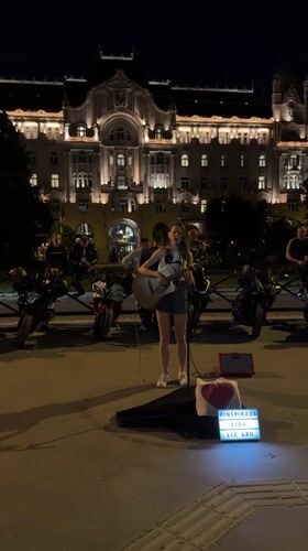 Street musician performs acoustic set in Budapest evening scene