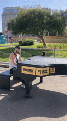 Man performs on grand piano in sunny urban plaza