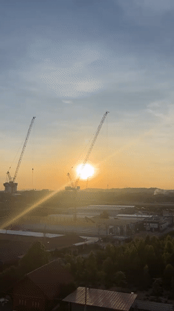 Sunrise captured between construction cranes in Pattaya City