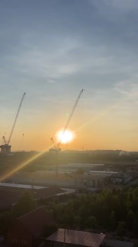 Sunrise captured between construction cranes in Pattaya City