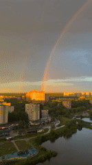 City skyline at golden hour, rainbow and dramatic clouds overhead