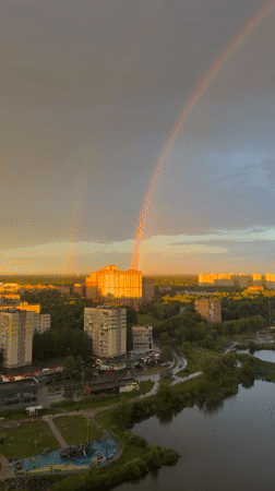 City skyline at golden hour, rainbow and dramatic clouds overhead