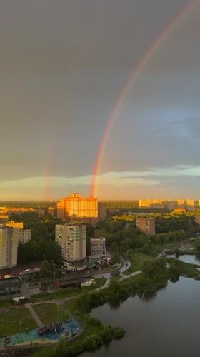 City skyline at golden hour, rainbow and dramatic clouds overhead