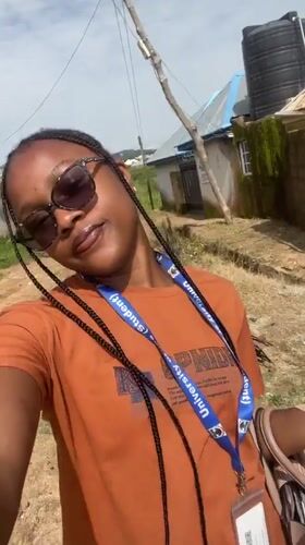 University of Jos student with credentials and rolled document, campus grounds