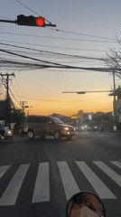 SUV makes left turn at Denpasar intersection during sunset
