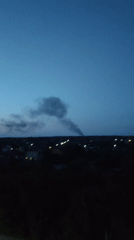 Dark smoke rises over residential area at twilight