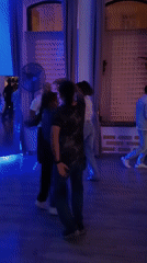 Couples practice salsa dancing in blue-lit studio session