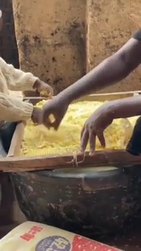 Child helps adults process grain in Nigerian community operation