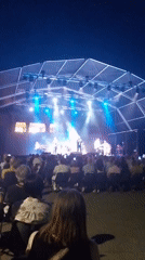 Outdoor concert stage lit up under a night sky