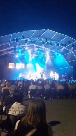 Outdoor concert stage lit up under a night sky