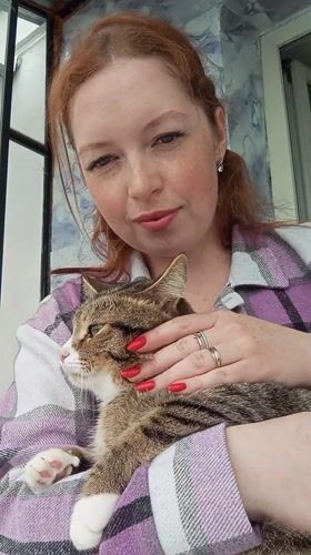 Woman holds tabby cat in Yurgamysh, Russia