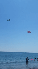 Packed summer beach day in Constanța with jet skis and a banner plane