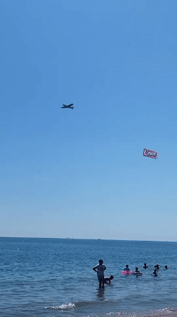 Packed summer beach day in Constanța with jet skis and a banner plane