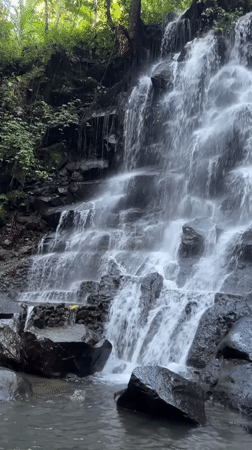 Multi-tiered waterfall documented flowing over rocks in Gianyar, Indonesia