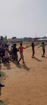 Children practice marching band on dirt field in Nigeria