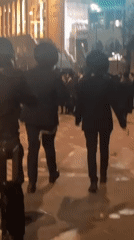 Traditional-dressed crowd walks through paper-strewn Jerusalem streets