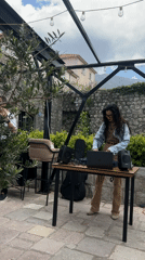 Woman DJs outdoors with laptop setup in Dobrota, Montenegro