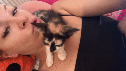 Woman cuddles calico kitten in tender moment in Kuta