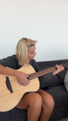 Woman plays acoustic guitar on couch in North Kuta