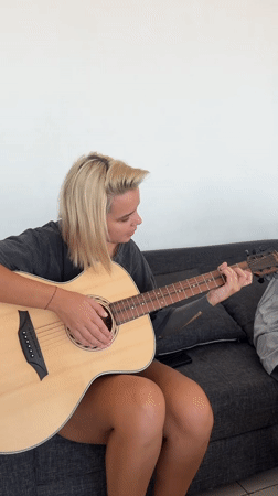 Woman plays acoustic guitar on couch in North Kuta