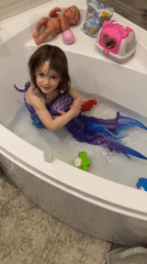 Toddler enjoys mermaid costume bath time with toys