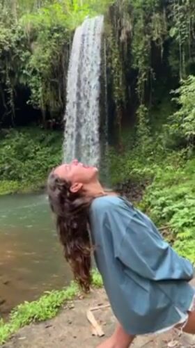 Tourists Document Waterfall Visit in Indonesian Jungle Setting
