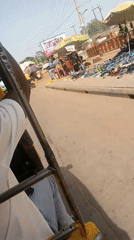 Auto-rickshaw passenger travels through busy Nigerian market district