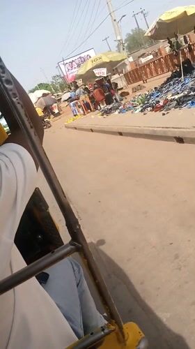Auto-rickshaw passenger travels through busy Nigerian market district