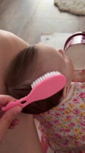 Parent brushes baby's hair during morning routine in Russia