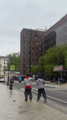 Two men perform synchronized martial arts routine on Moscow sidewalk