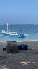 Person rests on calm Denpasar beach at dawn