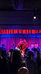 Live band performance at a red-curtained indoor venue