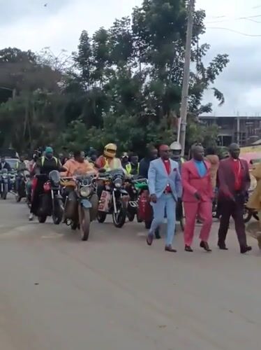 Suited men lead procession through busy Maua ward street