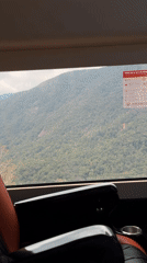 Passenger observes forested mountains from moving vehicle in Vietnam