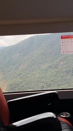 Passenger observes forested mountains from moving vehicle in Vietnam