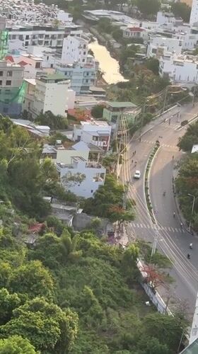 Aerial sweep of Nha Trang where city meets forested mountains