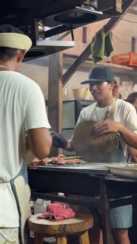 Street vendors grill meat skewers in General Luna