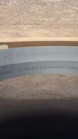 The video shows a close-up view of a stone plaque with the inscription "No free man shall be seized or imprisoned, or stripped of his rights or possessions..." The plaque is set into the ground, surrounded by sand or dirt. A wooden border is visible above the plaque. The camera slowly pans along the plaque, revealing more of the inscription.