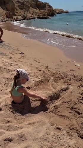 Child plays buried in sand on Sharm El Sheikh beach