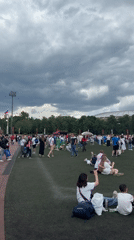 Crowd gathers on field near stadium under overcast skies