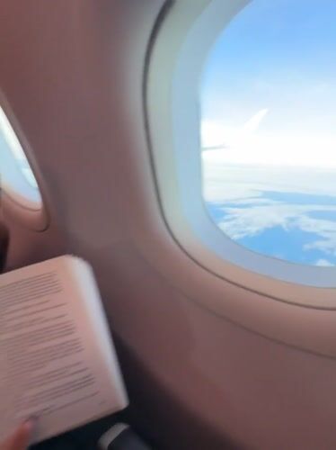 Passenger reads book during flight over Thailand