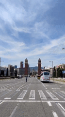 Pedestrian crosses Barcelona street near tall towers
