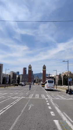 Pedestrian crosses Barcelona street near tall towers