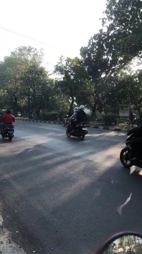 Motorcycle-heavy traffic flows through Gelam, Indonesia at golden hour